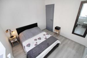 ein kleines Schlafzimmer mit einem Bett und einem Spiegel in der Unterkunft Gite-les-myrtilles in Corcieux