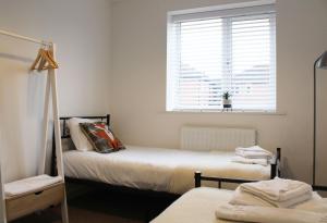a bedroom with two beds and a window with a window blind at Abingdon - Private Flat with Garden & Parking 01 in Abingdon