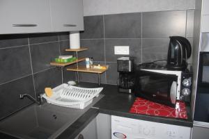 une cuisine avec un comptoir noir et un four micro-ondes dans l'établissement Gite-les-myrtilles, à Corcieux