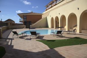 a patio with chairs and a swimming pool at Sunny Castillo Apartment in Costa de Antigua