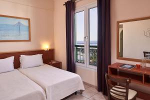 a bedroom with a bed and a desk and a window at Favie Suzanne in Tinos Town