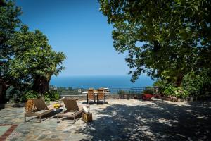 a patio with chairs and a table and the ocean at Helene Eco Luxury Villa in Tsagarada