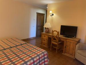 a bedroom with a bed and a flat screen tv at Hotel Garabatos in Navarredonda de Gredos
