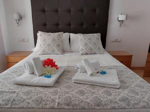 a bed with two towels and two flowers on it at Apartamento Nerja Beach in Nerja