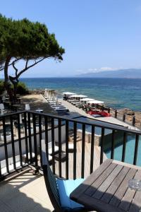 a balcony with a table and chairs and the ocean at Hôtel Castel d'Orcino in Calcatoggio