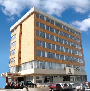 キトにあるHotel Republicaの駐車場に車が駐車されている建物