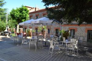 an outdoor patio with tables and chairs and umbrellas at Hostal Aribel Longinos in Cercedilla