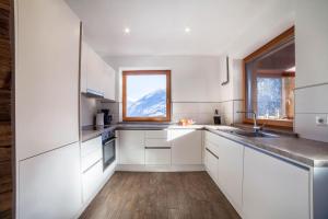 a kitchen with white cabinets and a window at Chalet Ebnerhof in Rifiano