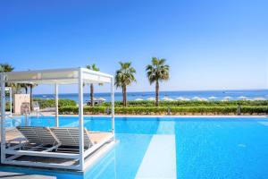 InterContinental Fujairah Resort, an IHG Hotel في العقة: حمام سباحة مع الكراسي والمحيط في الخلفية