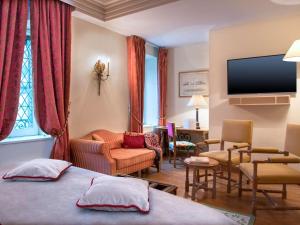a hotel room with a bed, television, and couch at Hotel de la Cité & Spa MGallery in Carcassonne