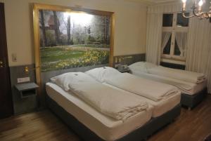 ディンケルスビュールにあるホテル レストラン ゴルデネス ラムの壁に絵画が飾られた部屋のベッド2台