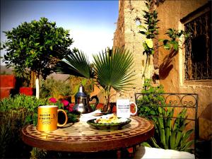 uma mesa com uma tigela de comida e duas canecas de café em Maison d'hôte ''J'' em Agdz