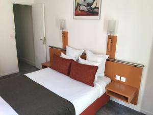 Schlafzimmer mit einem Bett mit weißer Bettwäsche und roten Kissen in der Unterkunft Hotel Morand in Rouen