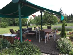 una terrazza in legno con baldacchino verde, tavolo e sedie di Aktiv pihenés apartman a Révfülöp