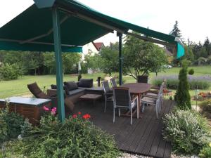 drewniany taras z zielonym baldachimem oraz stołem i krzesłami w obiekcie Aktiv pihenés apartman w mieście Révfülöp