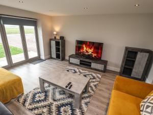 a living room with a fireplace and a tv at Acacia Barn in Boston