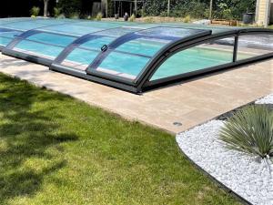 a swimming pool with a glass roof in a yard at Le gîte de Poulas in Couffy