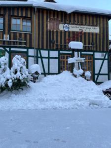 un cartel cubierto de nieve frente a un edificio en Gasthof & Pension "Schwarzer Adler", en Masserberg