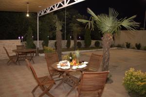 a patio with a table and chairs and a palm tree at Hotel Agava in Tbilisi City