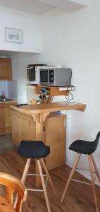 a kitchen with a table with a microwave and two chairs at Le Français, studio au calme proche de la gare in Besançon