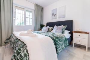 sypialnia z dużym białym łóżkiem z ręcznikiem w obiekcie Lovely 2 Bedroom Apartment w/ large garden + pools w mieście Benalmádena +20 zdjęć