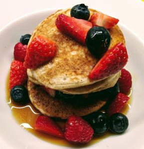 a stack of pancakes with strawberries and berries on a plate at Lee House in Lynton