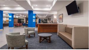a lobby with a couch and chairs and a bar at Holiday Inn Express Hotel & Suites La Place, an IHG Hotel in Laplace