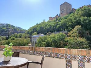 una mesa y sillas en un balcón con un castillo en Casa yamur bajo la Alhambra, en Granada