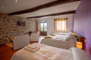 a bedroom with two beds and a stone wall at O Canto da Terra in Pantón