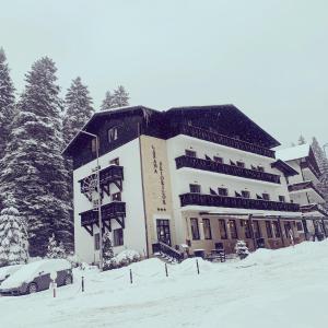 a large building in the snow with a car at Manor Ski Hotel in Predeal