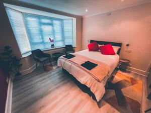 a bedroom with a bed with red pillows and a window at Modern 3 ground floor Parking and Garden in Bournemouth
