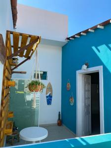 a room with a blue wall and a table with a swing at Villa Maragogi Hostel in Maragogi