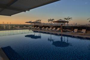 Eine Frau geht an einem Pool in einem Hotel vorbei in der Unterkunft Novotel Jumeirah Village Triangle in Dubai