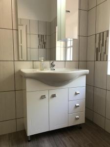 a bathroom with a white sink and a mirror at Tisza-Kert Apartmanok in Tiszafüred