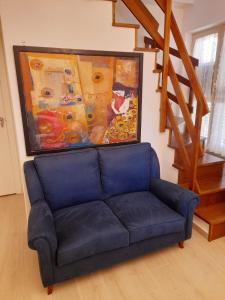 San Pietro的住宿－Cava Resort Costa d'Amalfi，客厅里一张蓝色的沙发,上面有绘画作品
