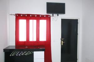a room with a red window and a tv at Académico do Sal in Espargos