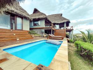 a villa with a swimming pool in front of a house at The Beach House in Inhambane
