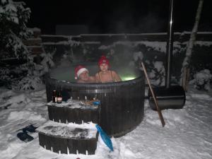 twee mensen in een bubbelbad in de sneeuw bij dom całoroczny na Kaszubach Nietoperek, prywatna balia, bania ruska, prywatna sauna in Załakowo