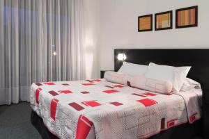 um quarto com uma cama com uma colcha vermelha e branca em Gran Hotel Fray Bentos em Fray Bentos