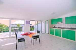 uma cozinha com armários verdes e uma mesa e cadeiras em Brezza dell'Alento em Marina di Casalvelino