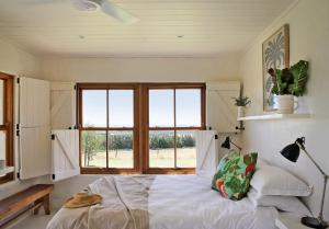 a bedroom with a bed and a large window at BoPlaas Country Cottages in Wellington