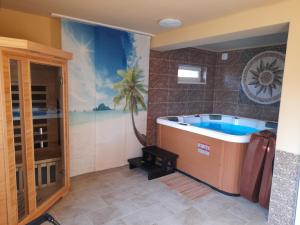 uma casa de banho com uma banheira com um mural de palmeira em Fónagy Apartmanok em Nagyvisnyó