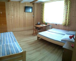 1 Schlafzimmer mit 2 Betten, einem Schreibtisch und einem TV in der Unterkunft Pokoje Gościnne U Danuty in Gliczarów Górny