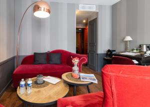 a living room with a red couch and a table at Hôtel Alexandra in Lyon