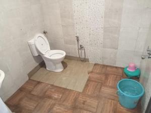 baño con aseo y cubo de agua en Chunmun Cottage en Pachmarhī