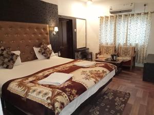 una habitación de hotel con una cama grande y una silla en Chunmun Cottage en Pachmarhī