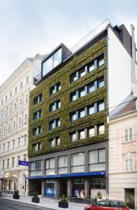 un alto edificio di mattoni con una macchina rossa parcheggiata di fronte di Hotel Gilbert a Vienna