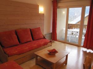 ein Wohnzimmer mit einem roten Sofa und einem Tisch in der Unterkunft Le Paradis d'ARAN in Luchon
