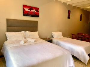 two beds in a room with a table and chairs at The Eden Lodge Boksburg in Boksburg +11 photos