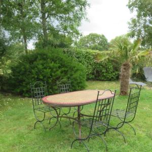 une table entourée de quatre chaises dans l'herbe dans l'établissement LE PETIT NID DANS LA ROULOTTE, à Roscanvel